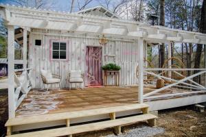 cobertizo blanco y rosa con terraza de madera en Camp Swann, en Tracy City