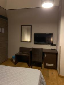 um quarto com uma cama, uma secretária e uma televisão em Hotel Pino em Lerici