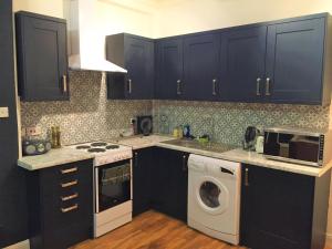 a kitchen with black cabinets and a washer and dryer at Glamours stylish Victorian apartment near city centre in Edinburgh