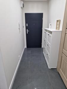 a kitchen with a black door and a tile floor at Słoneczny Apartament in Suwałki