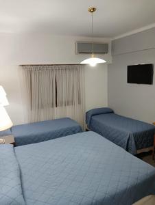 1 dormitorio con 2 camas y TV. en Hotel Neptuno en Mar del Plata