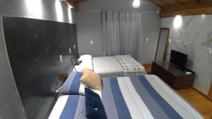 um quarto de hotel com duas camas e uma televisão em Moradas Desterro, próximo ao aeroporto 24 em Florianópolis