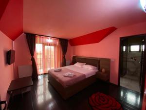 a bedroom with red walls and a bed and a window at Casa Dor de Lac in Salcioara