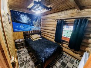 mały pokój z łóżkiem w drewnianym domku w obiekcie Котедж в Карпатах w mieście Huklyvyy