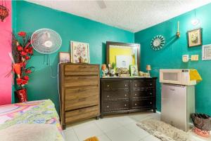 a bedroom with blue walls and a dresser and a mirror at Colorful Private Room Oasis in Montego Bay