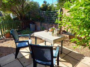 einen Tisch und Stühle in einem Garten mit Tisch und Stühlen in der Unterkunft Sunshine Cottage in Kapstadt