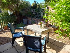 a table and chairs in a garden with a table and chairs at Sunshine Cottage in Fish Hoek