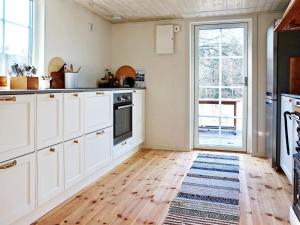 a kitchen with white cabinets and a wooden floor at 5 person holiday home in YXLAN in Yxlö