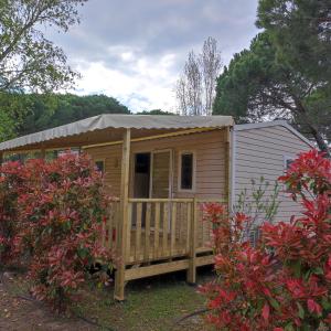 a large wooden cabin with a porch in a yard at Mobil Home Camping Elysée Vagues Océanes in Le Grau-du-Roi