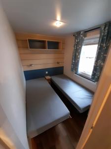a small room with two beds and a window at Mobil Home Camping Elysée Vagues Océanes in Le Grau-du-Roi