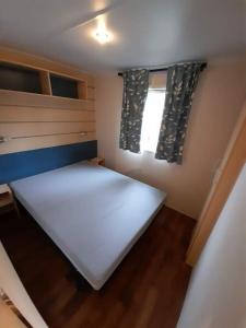 a small bedroom with a white bed and a window at Mobil Home Camping Elysée Vagues Océanes in Le Grau-du-Roi