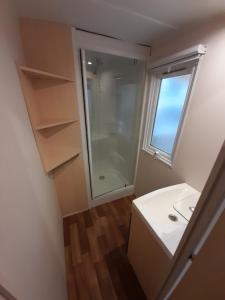 a bathroom with a shower and a sink and a window at Mobil Home Camping Elysée Vagues Océanes in Le Grau-du-Roi