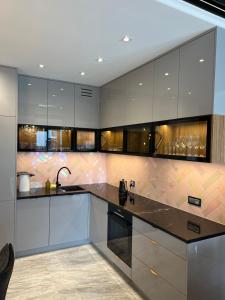 a kitchen with gray cabinets and a black counter top at Golden Life in Kielce +21 photos