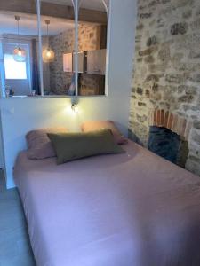 duże łóżko w pokoju z kamienną ścianą w obiekcie Appartement centre ville Quimper avec terrasse w mieście Quimper