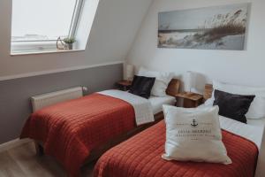 two beds in a small room with a red blanket at Deine MEERZeit in Büsum