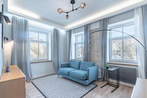 a living room with a blue chair and windows at Homly S22 in Rīga