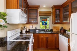 a kitchen with white appliances and wooden cabinets at Hale Hāhālua - Hale Hahalua - Serenity and Ocean Views in Kona now with AC in Kailua-Kona