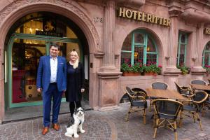 un hombre y una mujer y un perro delante de un hotel en Hotel zum Ritter St. Georg, en Heidelberg