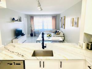 eine Küche mit einem Waschbecken und ein Wohnzimmer in der Unterkunft Stylish 1BR Condo 1Block to Aventura Mall in Aventura