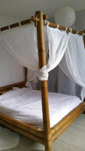 - un lit à baldaquin en bois avec des draps et des rideaux blancs dans l'établissement Maison de charme au calme à 10mn du centre ville, à La Rochelle