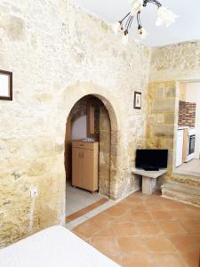 a room with a stone wall with a desk and a television at Lithos House and Studios in Kissamos