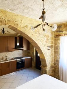 a kitchen with a stone wall and a chandelier at Lithos House and Studios in Kissamos