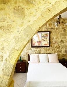 a bedroom with a bed in a stone wall at Lithos House and Studios in Kissamos