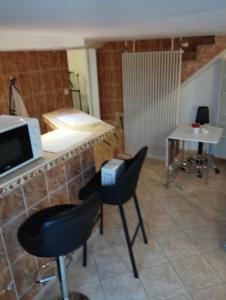 une cuisine avec des chaises noires et un comptoir avec un four micro-ondes dans l'établissement Studio meublé avec piscine partagée, à La Ferté-Gaucher