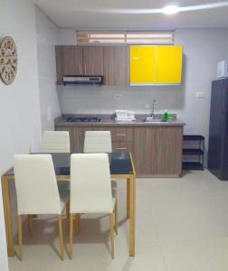 ブカラマンガにあるSachar Lodging Apartahotelのキッチン(ダイニングテーブル、白い椅子付)