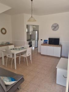 sala de estar y cocina con mesa y sillas en Vento d'Estate - Salento - Appartamento vicino al mare, en San Foca