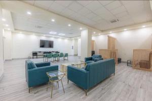 a waiting room with blue couches and a table and chairs at Rhythm & Blues Free Park 2BD-2BTH Near EWR-Penn-Prudential in Newark