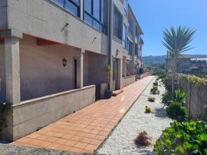 un trottoir vide à côté d'un bâtiment avec un palmier dans l'établissement Desconectaengalicia La Lanzada, 200m playa, à A Lanzada