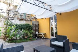 een patio met stoelen en een witte luifel bij The Secret Garden in Como