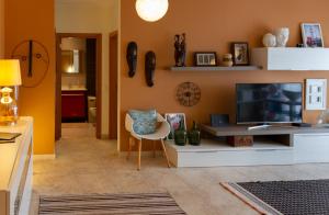 a living room with a television and a chair at Alojamento Nuno Moço in Peniche