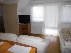 sala de estar con sofás blancos y TV de pantalla plana en Apartmaji Kranjska Gora, en Kranjska Gora