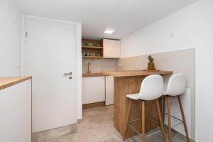una cocina con 2 sillas blancas y una barra en Apartmani Monika en Zaboric