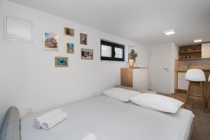 a white bedroom with a white bed and a kitchen at Apartmani Monika in Zaboric