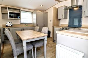 eine kleine Küche mit einem Holztisch und Stühlen in der Unterkunft Sunnyside - Willow View in South Cerney