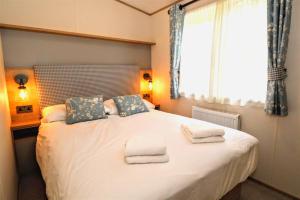 ein Schlafzimmer mit einem großen Bett mit Handtüchern darauf in der Unterkunft Sunnyside - Willow View in South Cerney