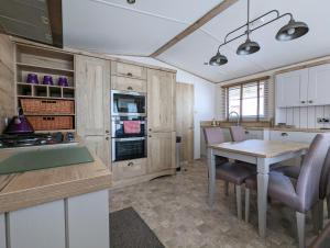 a kitchen with wooden cabinets and a table with chairs at Flamingo Lodge - Mallard Lake in South Cerney