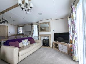 a living room with a couch and a flat screen tv at Flamingo Lodge - Mallard Lake in South Cerney