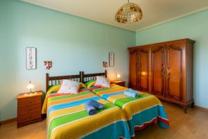 a bedroom with a large bed with yellow and blue sheets at Casa Rural La Sosiega con jardín privado in Bernueces
