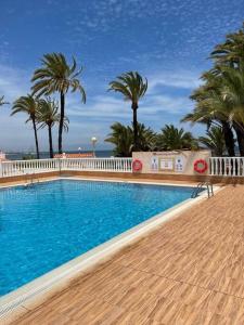 una piscina con palmeras y una valla blanca en Studio Cielo- pool, wi-fi & more, en Los Urrutias