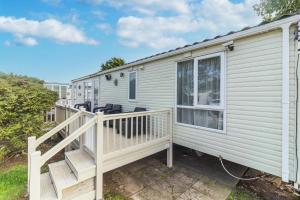 a mobile home with a porch and a deck at Luxury Caravan Nearby The Beautiful Scratby Beach In Norfolk Ref 50001a in Great Yarmouth