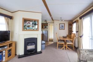 a living room with a fireplace and a dining table at 8 Berth Caravan For Hire At California Cliffs Holiday Park In Norfolk Ref 50046l in Great Yarmouth