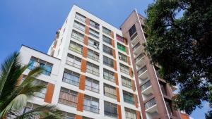 a tall white building with colorful windows and a palm tree at Caliview Apartahotel Andalaya in Cali