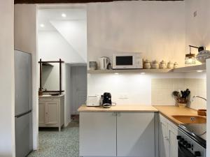 een witte keuken met witte kasten en een magnetron bij Housica & Co 2 in Ucciani