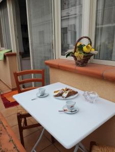 einen weißen Tisch mit einem Teller Essen und einem Obstkorb in der Unterkunft Casa ENGY in Terrasini