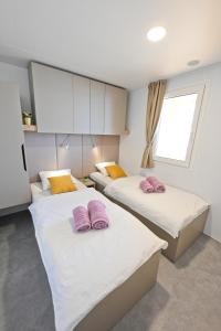 2 camas en una habitación con almohadas rosas. en O'LIVE PREMIUM Mobile Home, en Drage