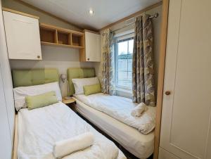 ein kleines Zimmer mit 2 Betten und einem Fenster in der Unterkunft Willow Lodge in South Cerney
